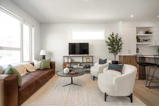 A living room with a brown couch, a white chair, and a coffee table.