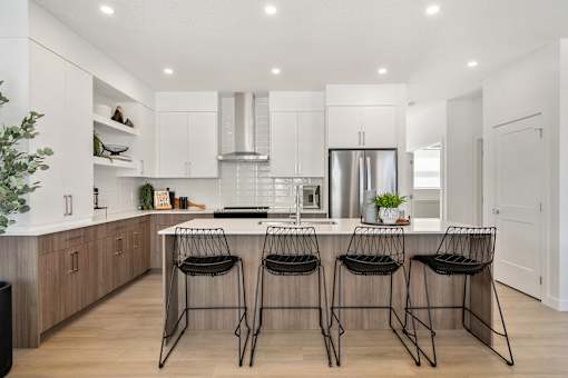 A modern kitchen with a bar area and three chairs.