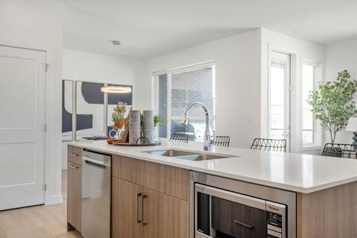 A modern kitchen with a white countertop and stainless steel appliances.
