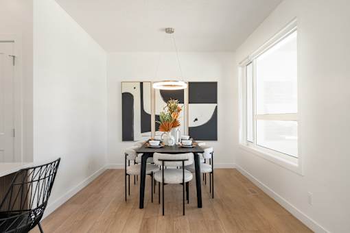 A dining room with a table set for two and a large painting on the wall.