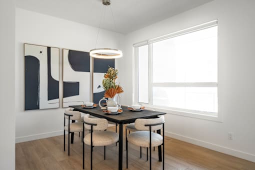 A dining room with a table set for two and a modern art piece on the wall.
