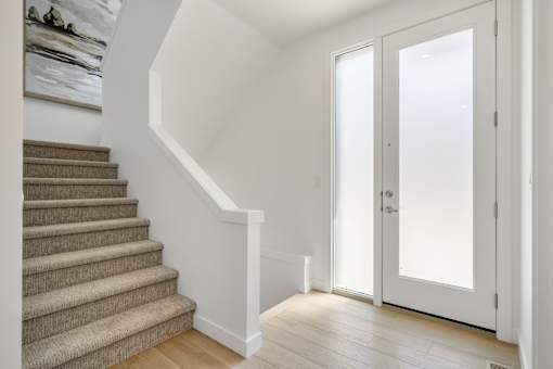 A staircase with a carpeted runner and a white wall.