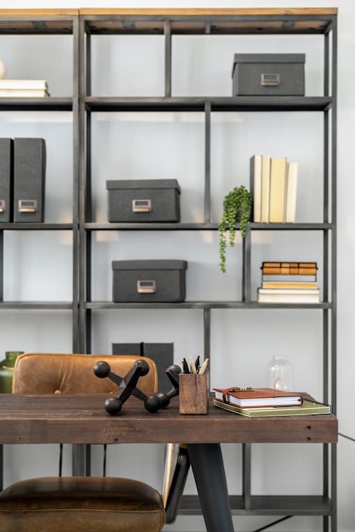 A shelf with books, binders, and a plant on it.
