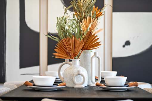 A table setting with a white vase and bowls.