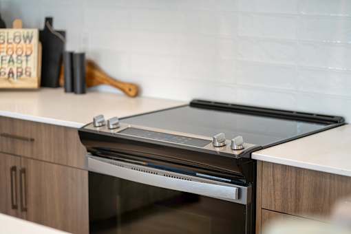 A modern kitchen with a stainless steel oven and wooden cabinetry.