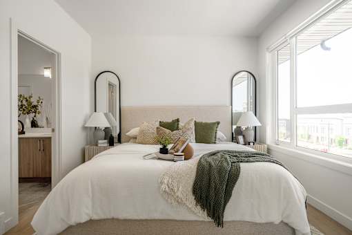 A bedroom with a large bed and two mirrors above it.