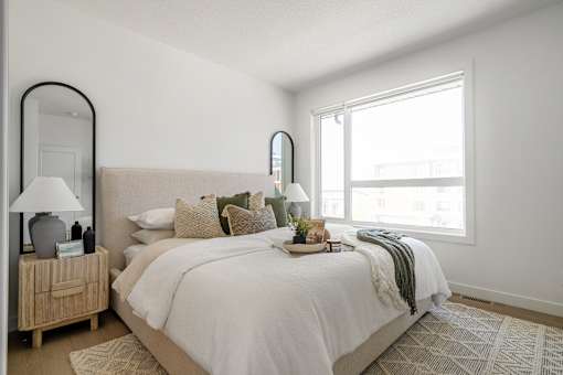 A bedroom with a large bed and a wooden nightstand.
