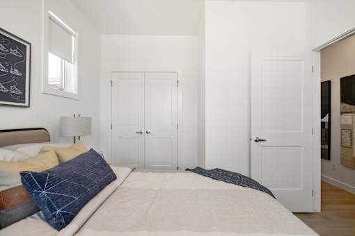 A bedroom with a bed, two closets, and a mirror.