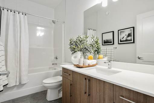 A bathroom with a white sink, toilet, and a shower with a white curtain.