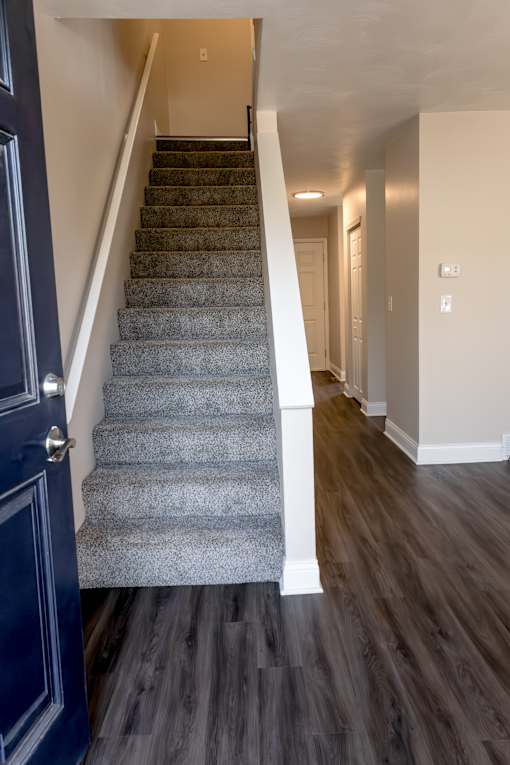 A staircase with a blue door on the left and wooden flooring.