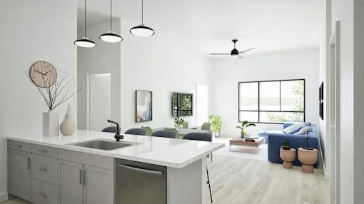 A modern kitchen with a large island and a bedroom in the background.