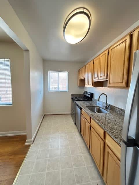 A kitchen with wooden cabinets and a black fridge.