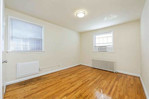 A room with wooden floors and a window with blinds.