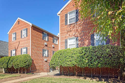 A red brick building with green bushes in front.