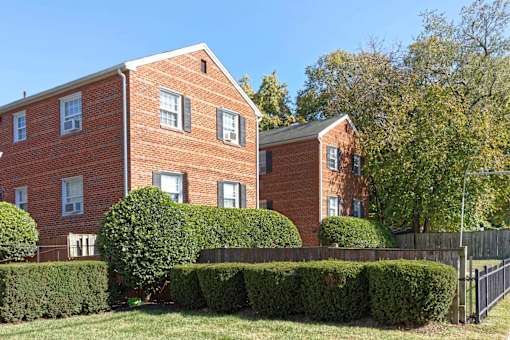 A red brick building with a black fence in front.