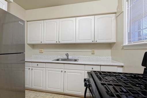 A kitchen with white cabinets and a black stove top.