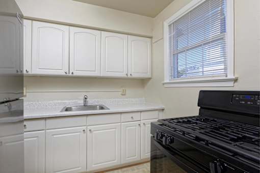 A kitchen with white cabinets and a black stove top oven.