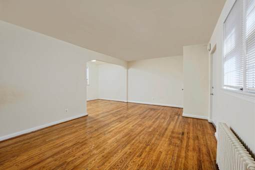 A room with wooden flooring and white walls.