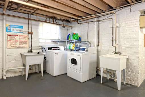 A laundry room with a washer and dryer, sink, and a sign on the wall.