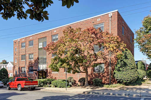 A red truck is parked on the street in front of a brick building.