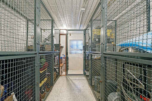 A long hallway with a metal fence on the left and a blue object on the right.