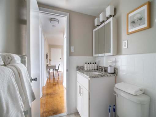 A bathroom with a toilet, sink, and mirror.