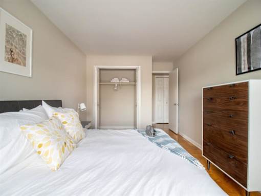A bedroom with a large bed and a wooden dresser.