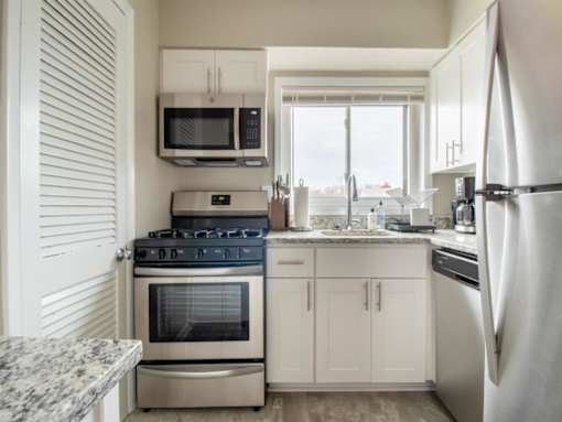 A kitchen with a stove, oven, refrigerator, microwave, and cabinets.
