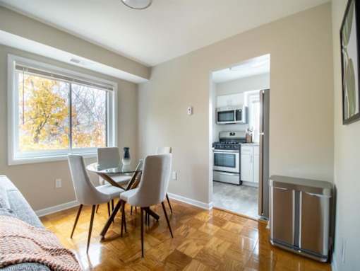 A kitchen with a table and chairs is visible from the living room.