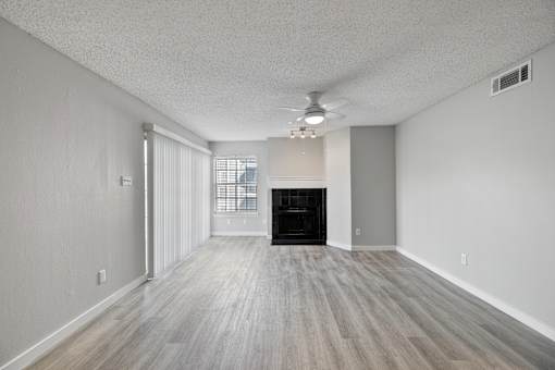 A spacious room with a fireplace and wood flooring.