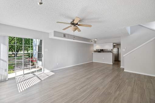 A spacious room with a ceiling fan and light wood flooring.