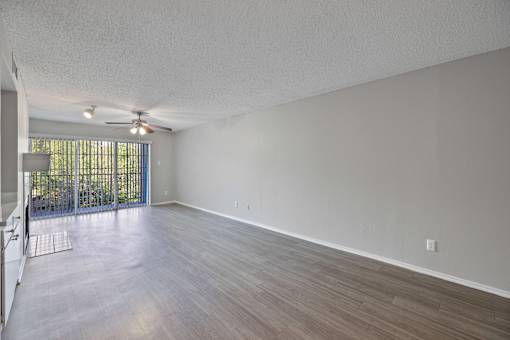 A room with a ceiling fan and sliding glass doors.