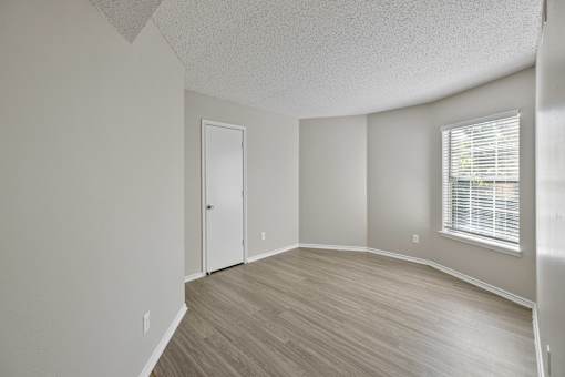 A room with a door, window, and wooden flooring.