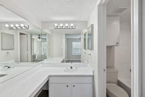 A white bathroom with a vanity and a toilet.