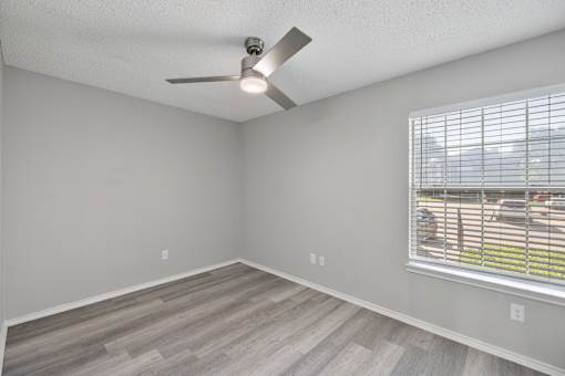 A room with a ceiling fan and a window with blinds.