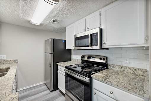 A kitchen with a black refrigerator, stove, and microwave.