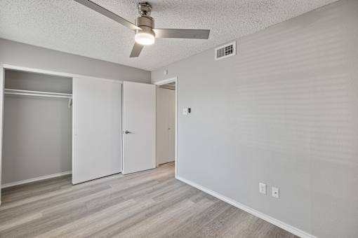 A room with a ceiling fan and a white door.