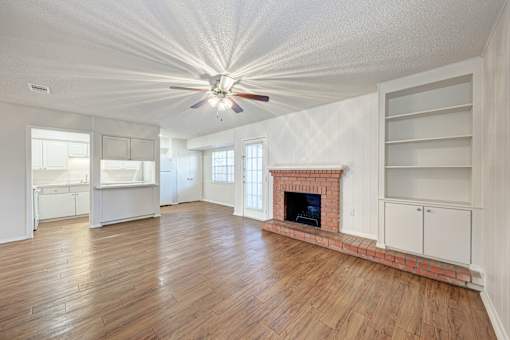 A large, empty room with a fireplace and wooden floors.