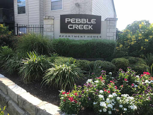 A sign for Pebble Creek Apartment Homes is in front of a building.