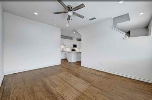 A room with a ceiling fan and wooden flooring.