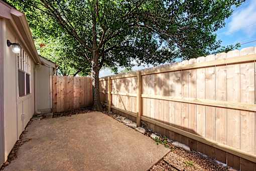 A backyard with a wooden fence and a tree.
