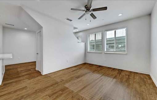 A room with a ceiling fan and wooden flooring.