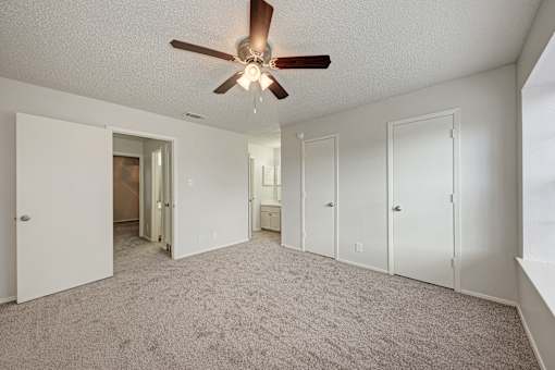 A room with a ceiling fan and carpeted floor.