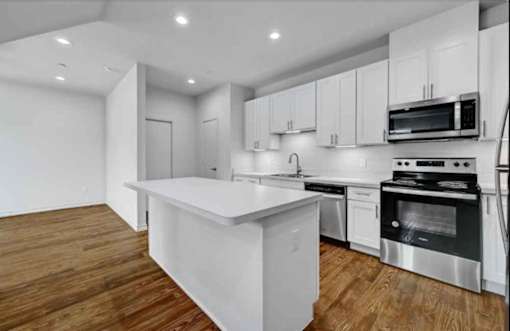 A modern kitchen with stainless steel appliances and wooden floors.