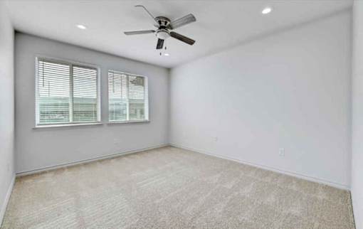 A room with a ceiling fan and carpeted floor.