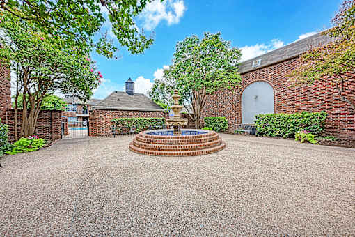 A courtyard with a fountain surrounded by a brick wall.