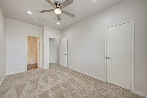 A room with a ceiling fan and carpeted floor.