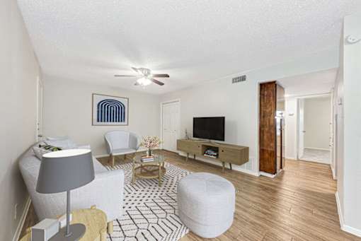 A living room with a television, a chair, a table, and a lamp.