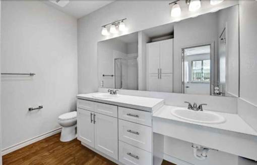 A white bathroom with a toilet, sink, and mirror.