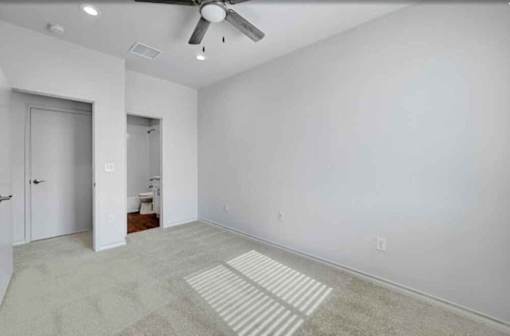 A room with a ceiling fan and a rug on the floor.